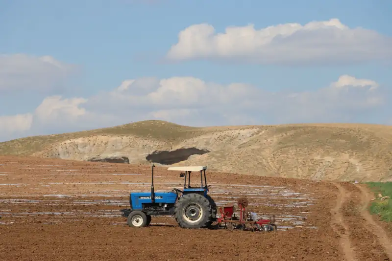 A tractor ploughing farmland under an open sky.