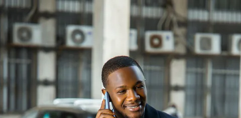 A man in a suit talking on a phone outdoors.