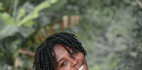 A woman in a floral top smiling outdoors.