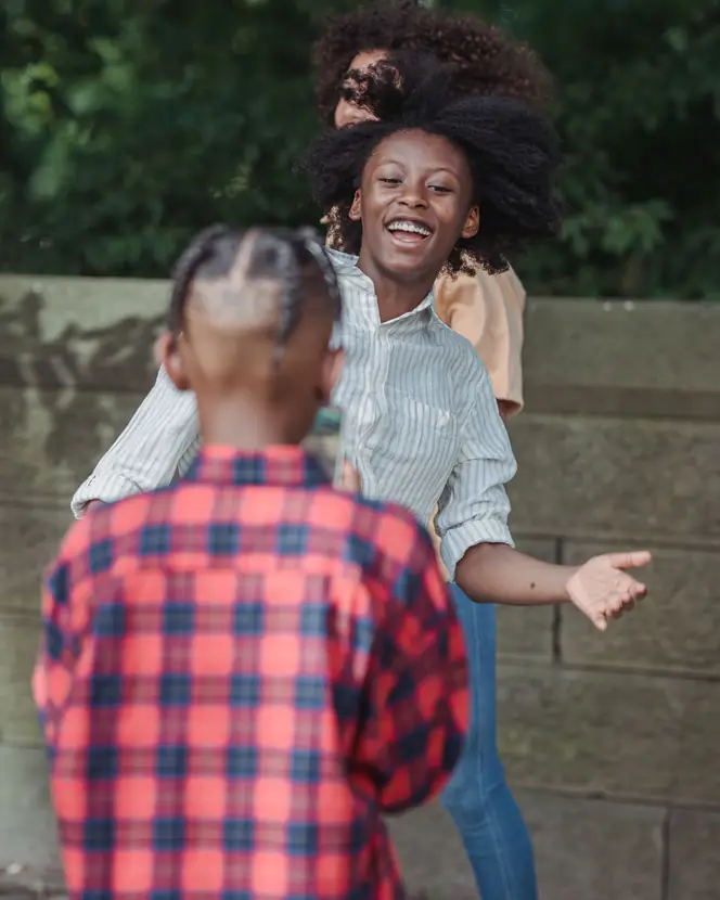 A mother and her children playing together outdoors.