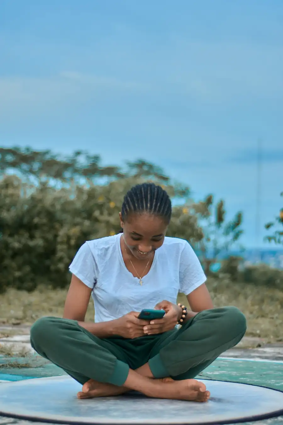 Young woman smiling while looking at her phone outdoors.