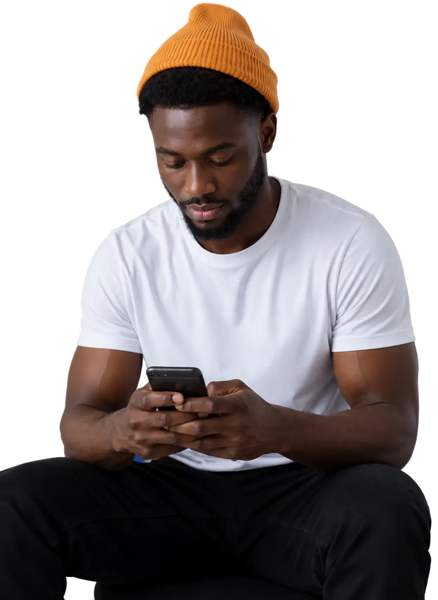 A man in a knitted beanie looking down at the phone in his hands.