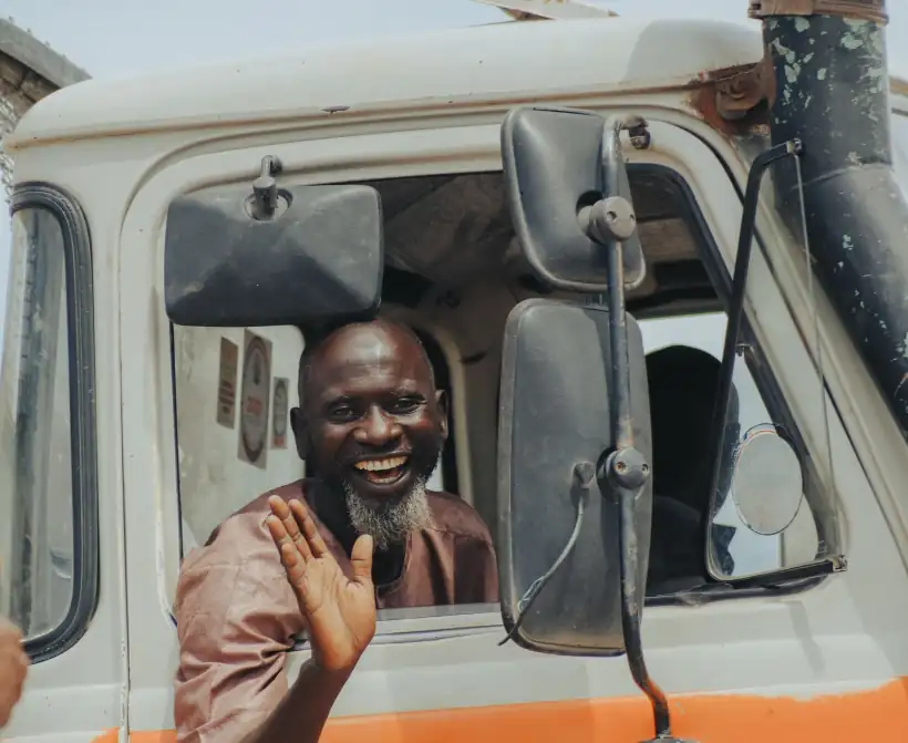 A haulage driver smiling and waving from the cab of his truck.